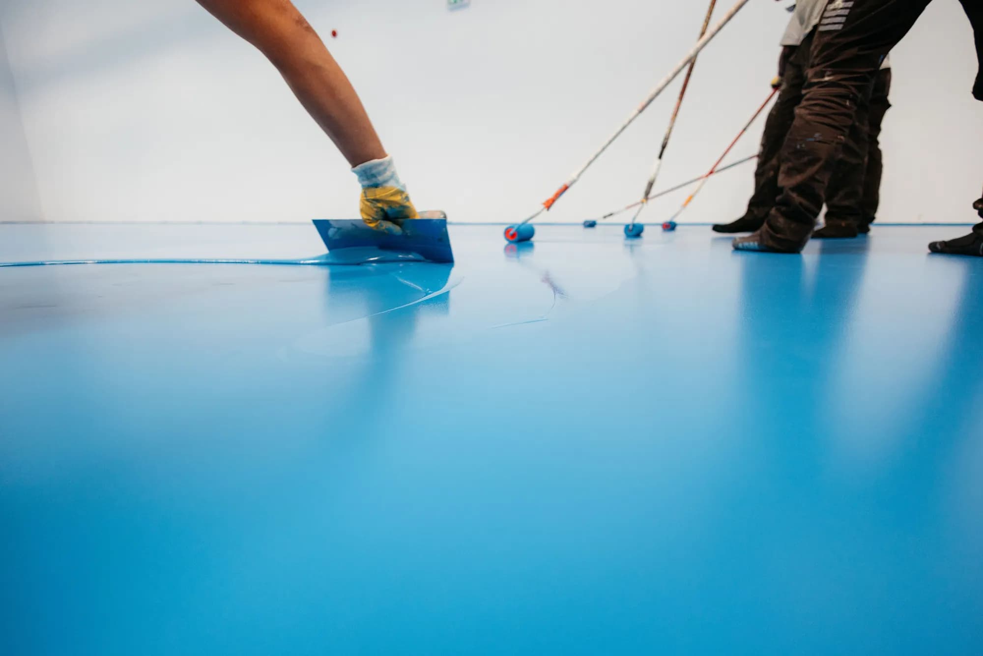 Verarbeitung einer blauen Bodenbeschichtung durch einen Fachhandwerker